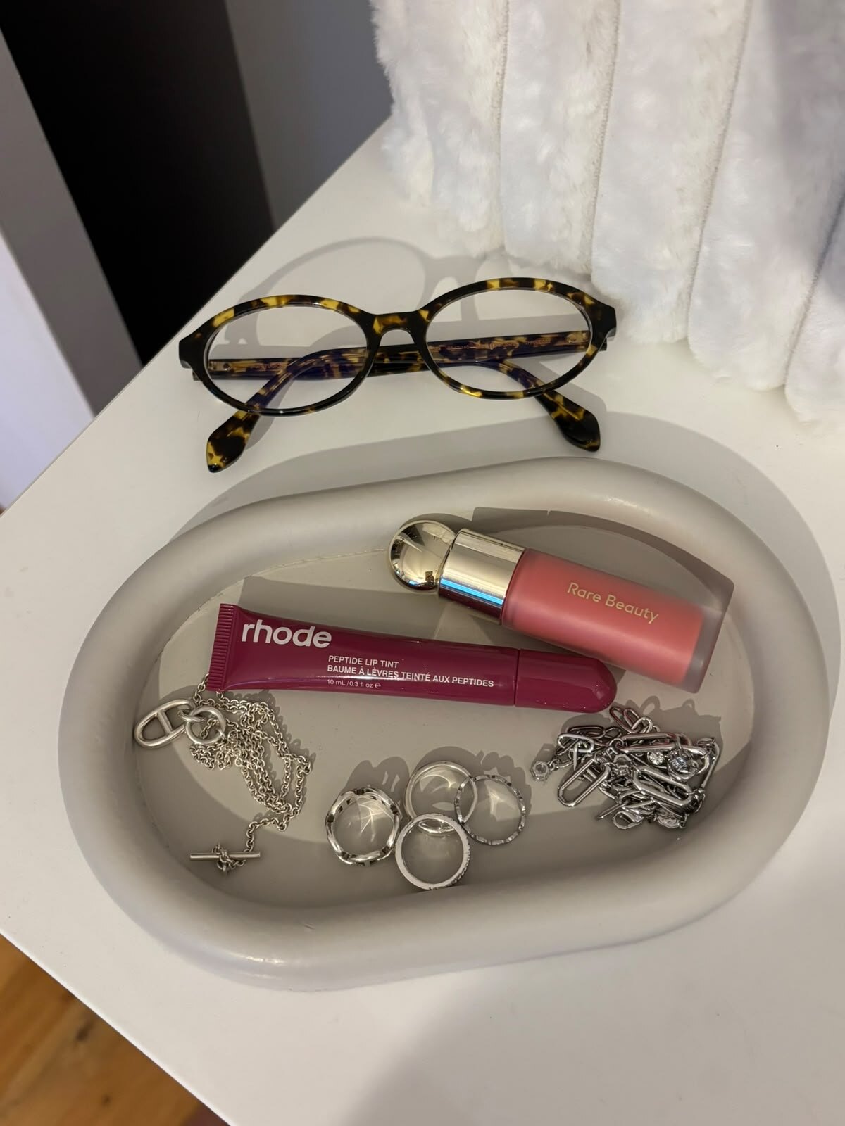 Composition de produits de beauté, bijoux argentés et lunettes.