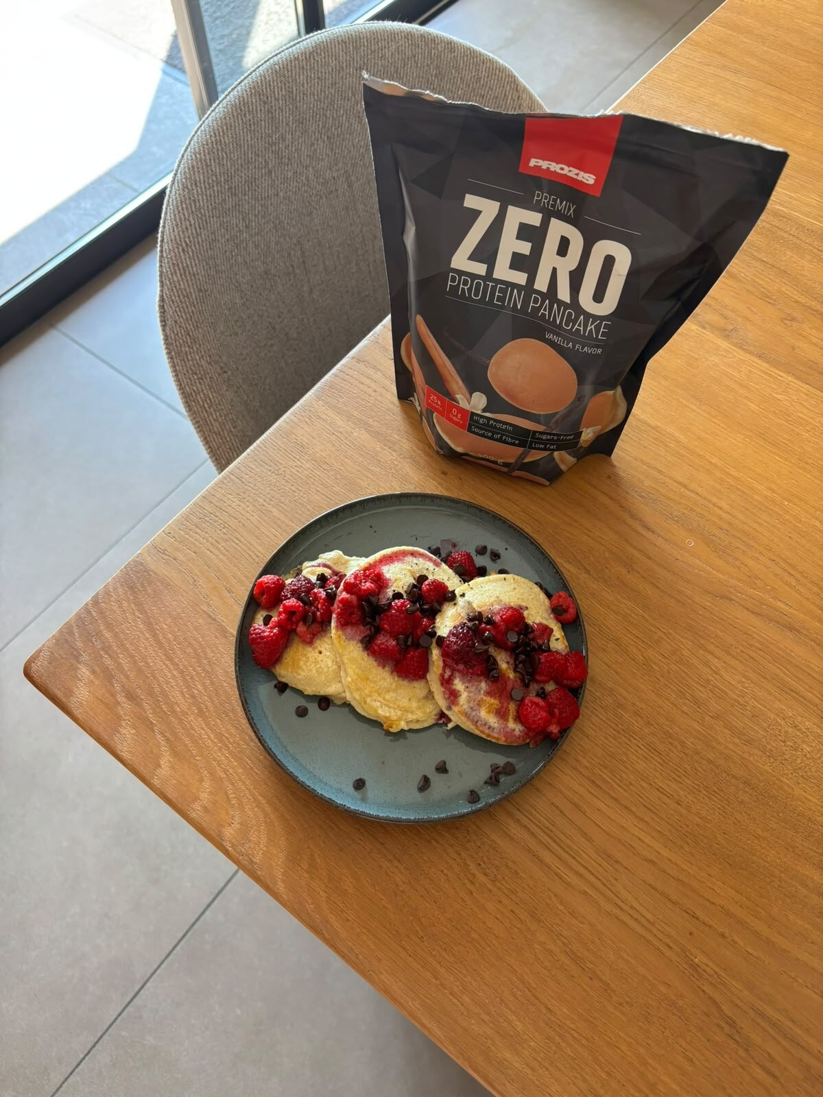 Assiette de pancakes protéinés aux fruits rouges, à côté du sachet Prozis.